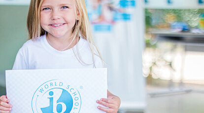 menina segurando um papel com o logo IB